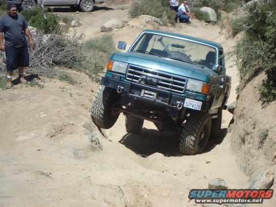 Teal 1987 Ford F-150 off-roading on a dirt trail