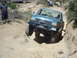 1986 Ford Bronco - This teal 1987 Ford F-150 is navigating a challenging off-road trail with a rocky incline.