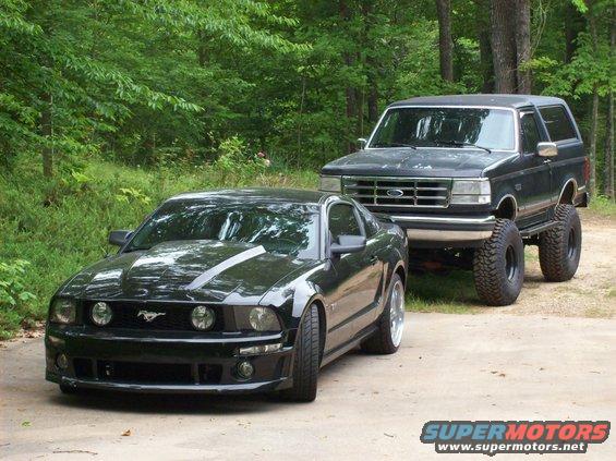 Black 2007 Ford Mustang parked in front of a lifted black Ford Bronco