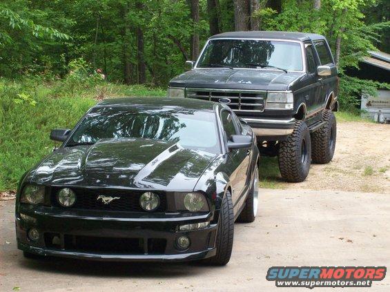 Black 2007 Ford Mustang parked next to a lifted Ford Bronco