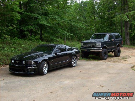 black Ford Mustang parked next to a lifted black Ford Bronco
