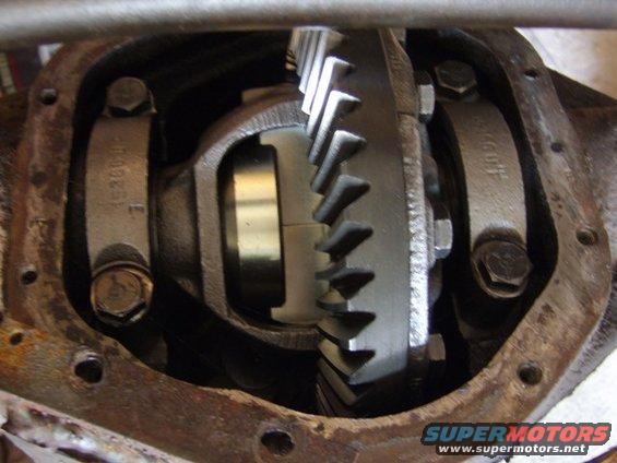 Close-up of differential gears inside a rusty housing. Part numbers are visible on the bearing caps