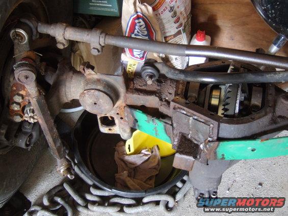 Close-up of a rusty Jeep Dana 44 axle housing with the differential cover removed, showing gears