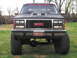1991 GMC Jimmy - This GMC pickup truck, likely from the late 1980s, has a prominent grille and is modified with off-road tires.
