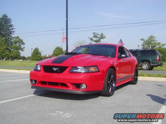 Red 2004 Ford Mustang with black racing stripes and hood scoop parked in a lot