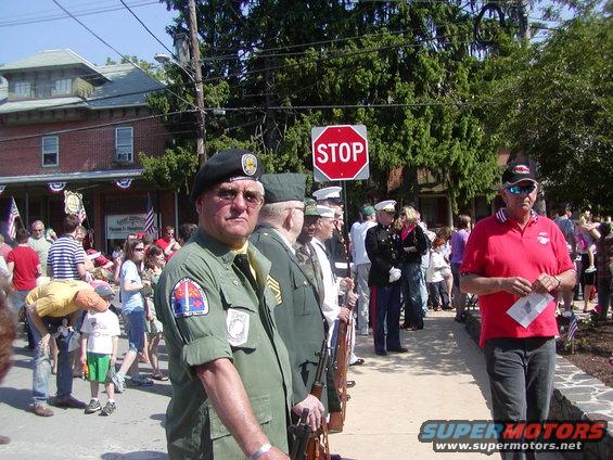 Veterans in uniform and civilians gathered outdoors, possibly for a parade or ceremony