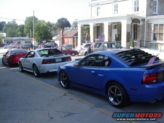 Blue 2004 Ford Mustang with louvers on rear window and American flag