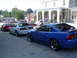 2004 Ford Mustang - Multiple Ford Mustangs parked in front of a building with American flags displayed.