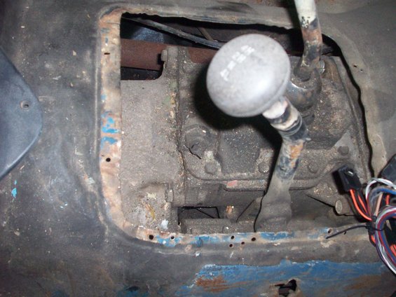 Jeep transmission tunnel with rust and exposed wiring, showing a four-wheel-drive shifter
