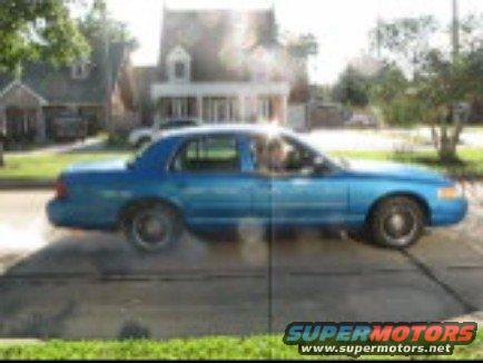 Blue 2001 Ford Crown Victoria driving down a suburban street