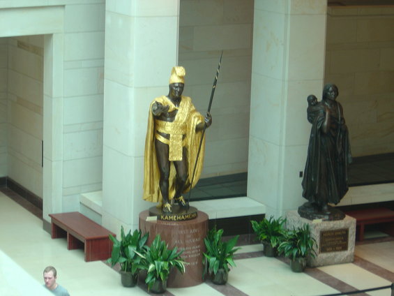 Statue of Kamehameha I in gold and bronze, holding a spear, with a second bronze statue of a woman holding a child to the right