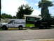 2000 Ford F-250 - A white 2000 Ford F-250 equipped with a camper tows a black truck on a trailer down a residential street.