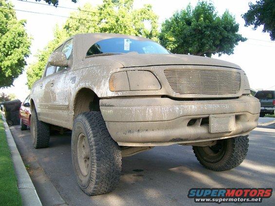 Mud-covered pickup truck with lifted suspension parked on a street