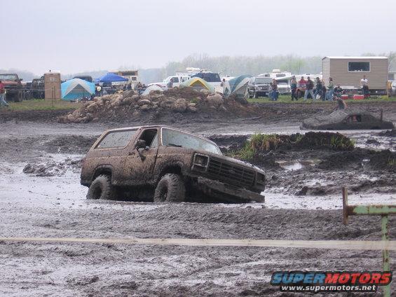 Mud-covered SUV stuck in mud, front-right wheel submerged