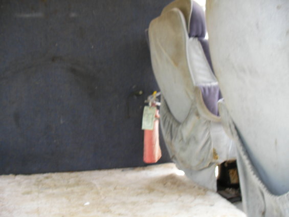 Interior shot of a vehicle showing a fire extinguisher mounted on the wall next to a seat