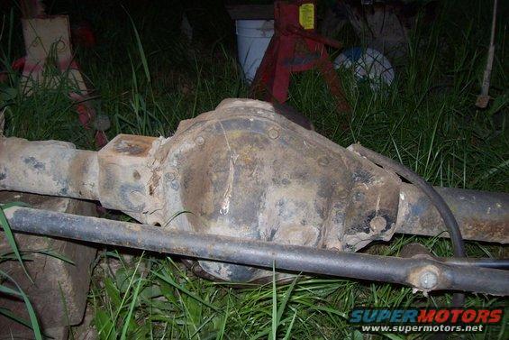 Rear axle differential assembly with brake line, resting on grass