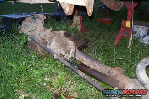 vehicle rear axle assembly sitting on grass, supported by jack stands