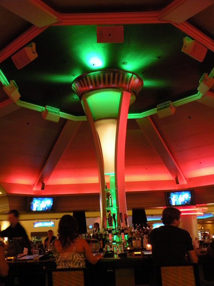 Interior of a bar with a central column illuminated by green and red lights