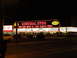 1989 Nissan 300ZX - Neon signs illuminate a General Store and Bonanza at night, with several vehicles visible in the parking lot.