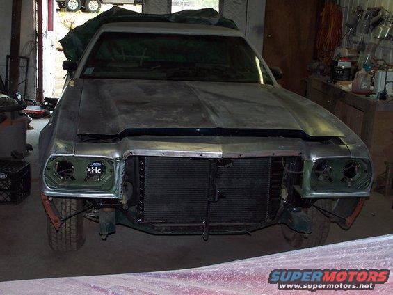 1975 Ford Ranchero front view in garage, hood up, grille exposed, headlights missing