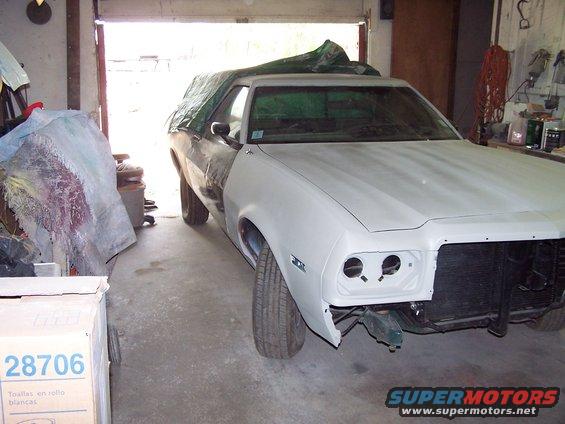 White 1975 Ford Ranchero in a garage, partially covered, with front end disassembled