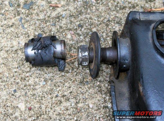 Damaged metal suspension component with torn rubber boot and exposed bolt