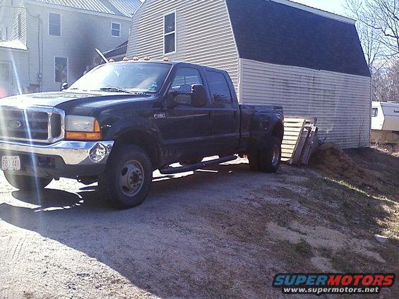 Dark blue Ford F-250 Super Duty pickup truck parked on a dirt lot next to a barn