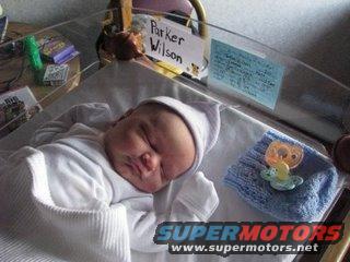Newborn baby sleeping in a hospital bassinet with a name tag reading 'Parker Wilson'