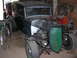 1931 Ford Model A - A modified hot rod with a distinctive green grille sits in a garage next to another vehicle.