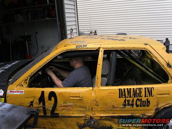 Yellow car with number 12 and 'DAMAGE INC 4x4 Club' on the side, driver inside