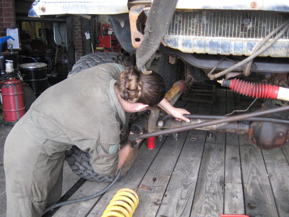 Person working on vehicle suspension, red shock absorber visible