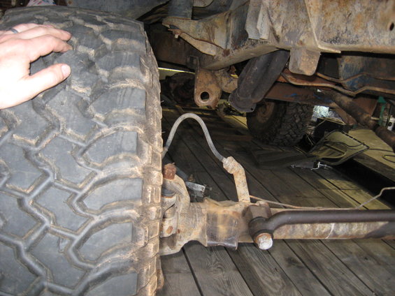 Close-up of a large off-road tire and suspension components on a wooden surface