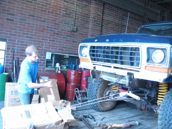 1978 Ford Bronco front end in a garage, man in blue shirt next to boxes