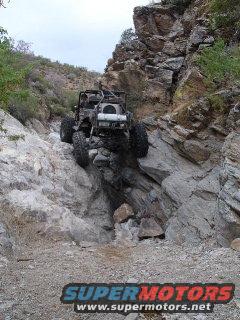 Two off-road vehicles navigating a steep, rocky trail with large tires