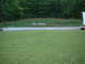 1971 Ford Torino - A car is parked beside a trailer on a lawn with a wooded area behind a retaining wall.