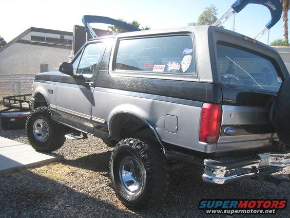 1994 Ford Bronco, lifted, two-tone silver and black, parked with a trailer behind it