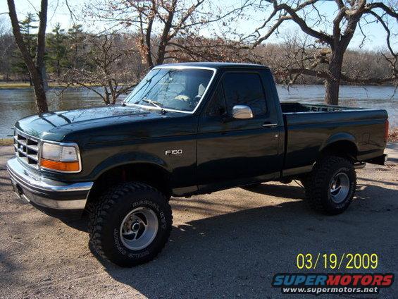 Dark green 1996 Ford F-150 pickup truck with lifted suspension and aftermarket wheels parked outdoors