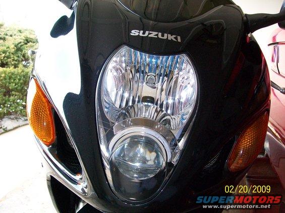 Black motorcycle front with Suzuki logo above dual headlights and orange turn signals