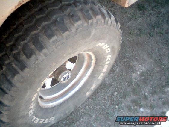 Tire with white lettering reading "MUD KING" and "STEEL" on a silver rim