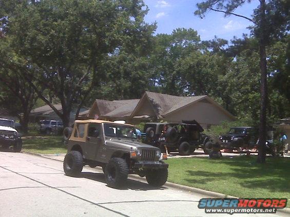 Tan soft-top Jeep Wrangler with large tires, parked on a street