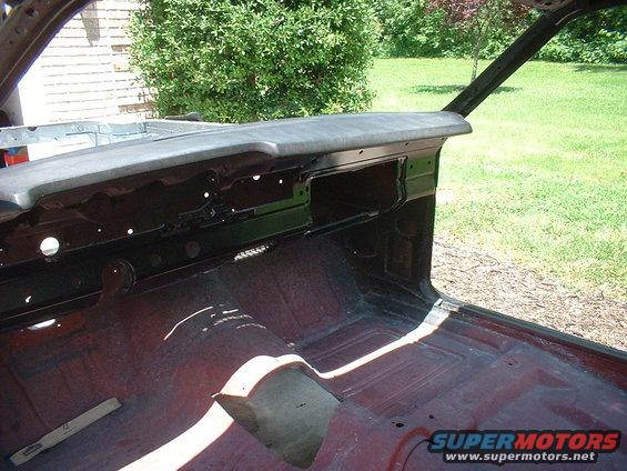 Car interior stripped down, showing bare metal floor and dash frame. Sunlight streams in
