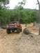1987 Suzuki Samurai - An orange off-road vehicle navigates a rocky trail surrounded by trees.