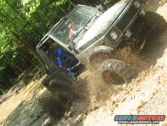 1987 Suzuki Samurai driving through mud, 3q-front view, olive green