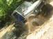 1987 Suzuki Samurai - This 1987 Suzuki Samurai navigates a muddy trail, kicking up dirt and water.