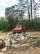 1987 Suzuki Samurai - An orange off-road vehicle navigates a rocky terrain in a wooded area.