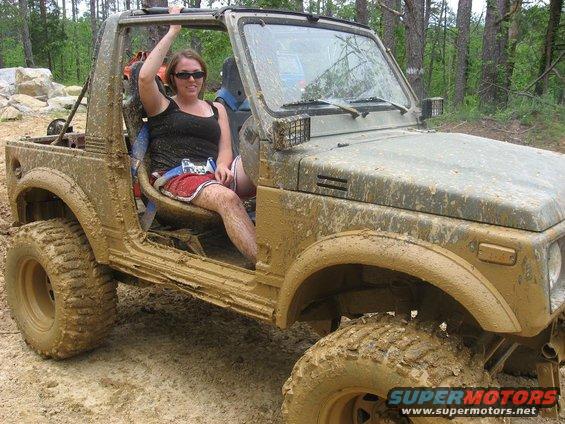 Muddy Suzuki Samurai with a woman in the driver's seat, off-roading