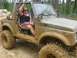 1987 Suzuki Samurai - A woman sits in a heavily mud-covered Suzuki Samurai, ready for an off-road adventure.