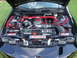2007 Ford Mustang - The engine bay features red hoses and a red strut bar, with a GM Performance Parts sticker on the radiator support.