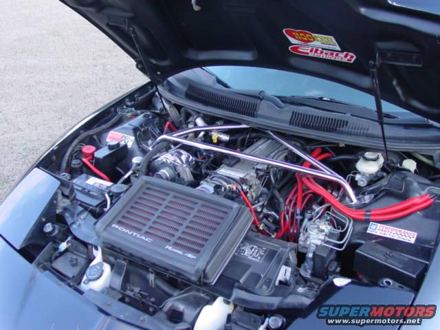 Engine bay of a Pontiac Firebird with red spark plug wires and an aftermarket air intake