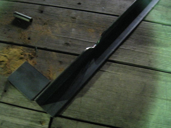 Metal square and cylindrical part resting on weathered wooden planks